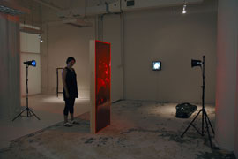 installation view of three sculptures, doorway, mummy bag, mirror 1, with a woman viewing doorway for scale