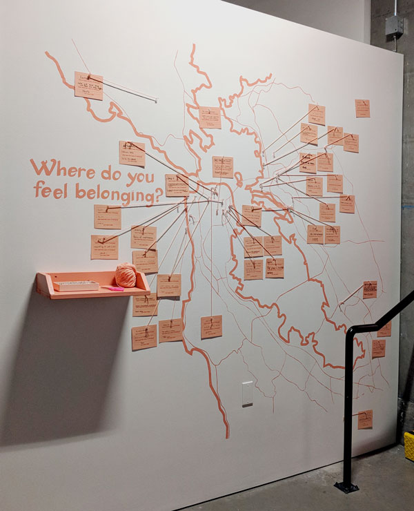 where do you feel belonging in the bay area. photo of a wall in a gallery. there's a map of the bay area painted on the wall, with a shelf with pins. there are cards marking specific places in the bay area.