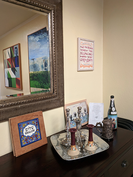 certificate next to a mirror with paintings in the reflection. Below are artworks and  Judaica.
