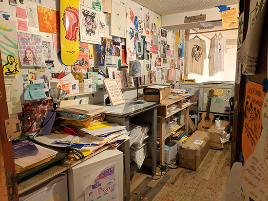 Certificate in a printing studio with prints, skateboard decks, and posters all over the walls.