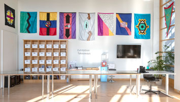 colorful flags of various original designs on the walls in a white room
