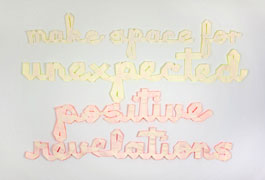 a wall installation with 'make space for unexpected' in cream grosgrain with a fluorescent yellow backing, and 'positive revelations' in cream grosgrain with a fluorescent orange backing. all text in cursive.