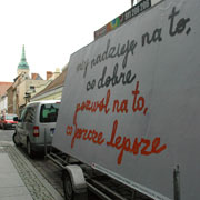 the artwork on a mobile billboard towed by a van in an old city street