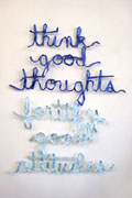 a wall installation of light blue and blue ribbons spelling out 'think good thoughts fortify good attitudes' in cursive