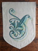 a neutral colored banner with a onion-shaped bottom. it has a floral ornamental design printed in blue-green, with two ligher shades printed in diagonal offset layers underneath.