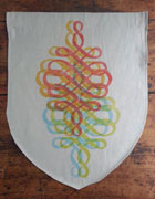 a neutral colored banner with the bottom shaped like a shield. it has a swirling, symmetrical, calligraphic flourish printed in red, orange, blue, and lime green. each color is slightly offset from one another.