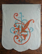 a neutral colored banner with a scalloped lower edge, with two ornamental designs, one in orange and one in blue, overprinted on each other.