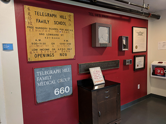 certificate among artifacts and historical signs along a wall painted red in a hallway