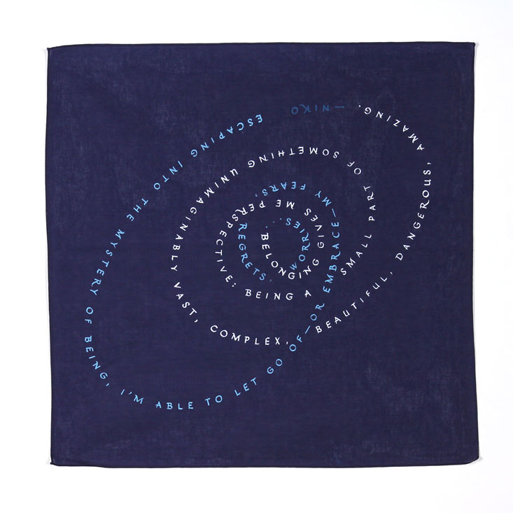 Navy Blue bandanna with text in blue and white that follows interlocking spiral design. The text reads: Escaping into the mystery of being, I’m able to let go of—or embrace—my fears, regrets,  worries... Belonging gives me perspective: being a small part of something unimaginably vast, complex, beautiful, dangerous, amazing. —Niko 