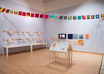 installation view of an exhibit, with color flags strung overhead