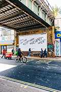 Photo of the artwork as a billboard in a graffitti-covered underpass on a London street.