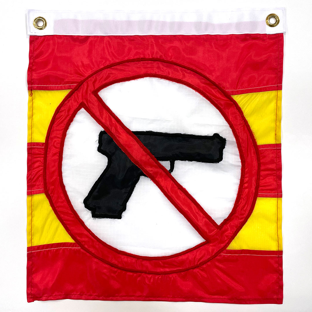 A sewn flag of a black handgun in a red circle with a line crossing it out. The circle is on a background of horizontal stripes of red and yellow.