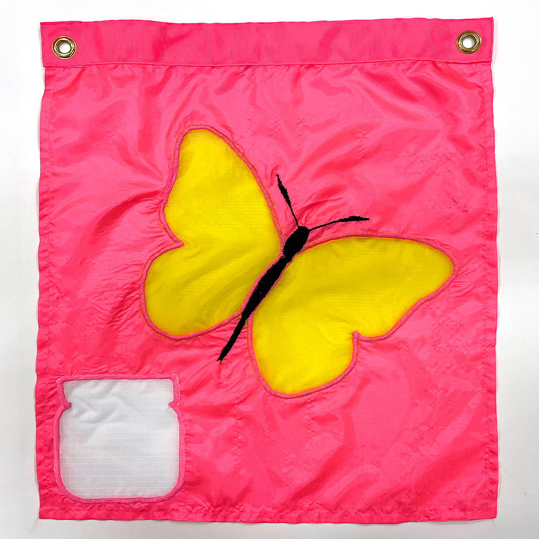 a sewn flag of a yellow butterfly with a black body flies away from a white jar on a pink background