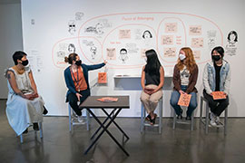 a group of people seated on stools in front of the installation of portraits and quotes