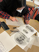 an asian girl drawing a portrait on vellum using a photo reference