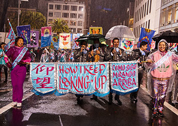 Colorful banners being marched in the street on a rainy night.