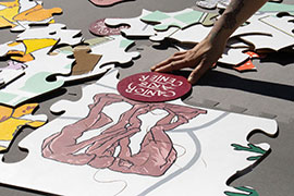a hand moves a puzzle piece with the text, Cantor Arts Center, into place beneath the illustration of the Rodin sculpture which was in the process of being painted in an earlier image.