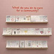 The pink wall with the question, what do you do to care for community, above shelves filled with cards.